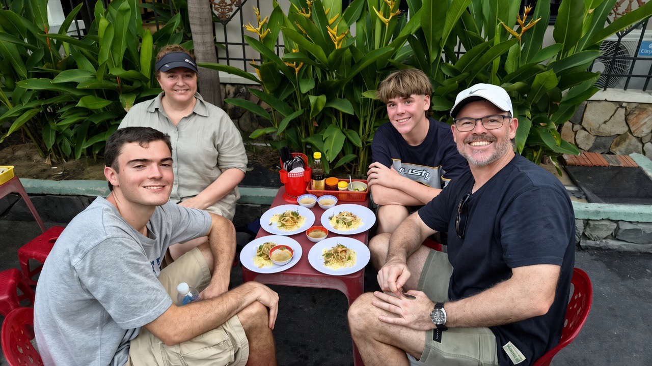 Travelers enjoying local Hoi An street food with a local tour guide